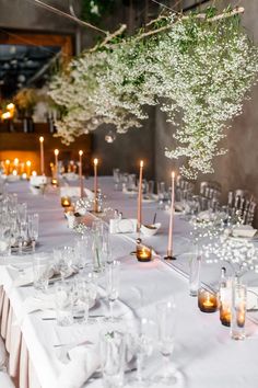 a long table with candles and flowers in vases on top of it is set up for a formal function