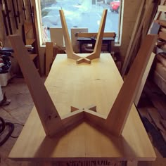 a wooden table with two chairs on it in front of a window and some wood planks