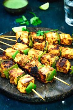 several skewers of food sitting on top of a black plate with green peppers