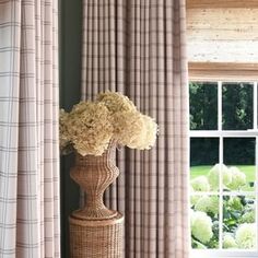 a vase with flowers on a table in front of a window