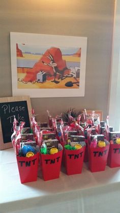 there are many small red buckets with candy in them on the table next to a chalkboard