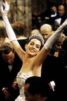 a woman wearing a tiara and holding her arms in the air