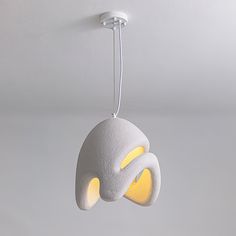 a white and yellow light fixture hanging from the ceiling in a room with gray walls