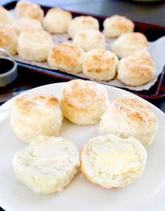 biscuits and butter on a plate next to a baking pan with other baked goods in the background