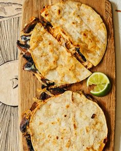 two quesadillas on a cutting board with lime wedges