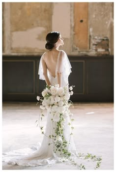 a woman in a wedding dress holding a bouquet of flowers and looking away from the camera