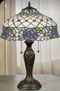 a stained glass lamp on a table with curtains in the background