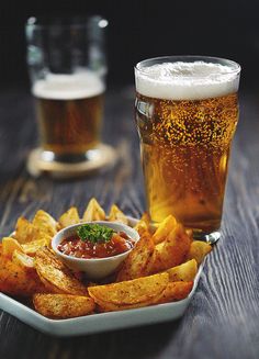 there is a plate of fries and a glass of beer on the table