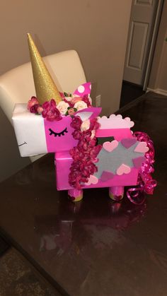 a pink pony made out of cardboard with flowers and a unicorn horn on it's head