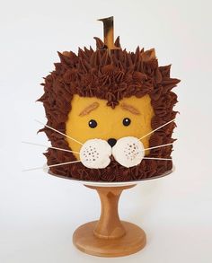 a cake shaped like a lion on top of a wooden stand with the number one on it's face