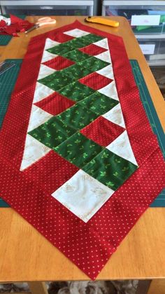 the table runner is made from red and green fabric, which has christmas trees on it