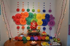 an arrangement of colorful paper fans and decorations on a table in front of a wall