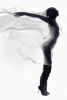 the silhouette of a woman in high heeled boots is shown with her arms outstretched