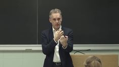 a man standing in front of a blackboard giving a lecture