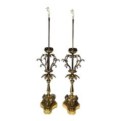 a pair of antique brass candlesticks with flowers and leaves on them, set against a white background