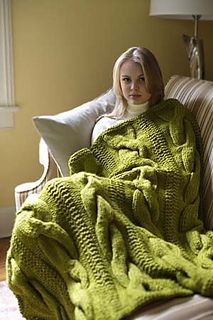 a woman sitting on a couch under a green blanket