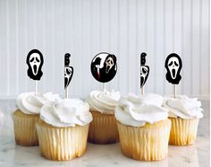 some cupcakes with white frosting and black faces on them are lined up