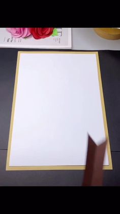 a white sheet of paper sitting on top of a table next to a vase with flowers