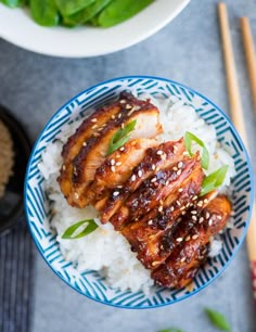 two plates filled with meat and rice next to chopsticks