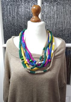 a woman wearing a multi colored necklace on top of a mannequin