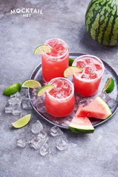 three watermelon margaritas on a plate with ice and lime wedges next to them