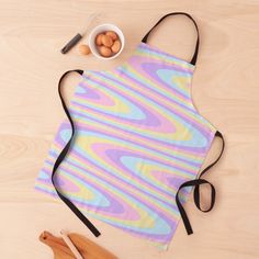 a colorful apron sitting on top of a table next to wooden spoons and utensils