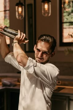 a man in white shirt holding up a metal object