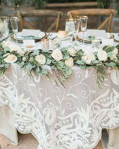 the table is set with white flowers and greenery