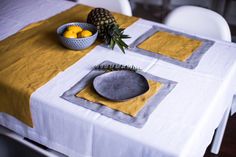 a pineapple sits on the table next to a bowl of fruit and napkins