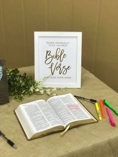 an open bible sitting on top of a table next to some markers and pencils