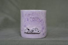 a ceramic mug with a dog on it that says i like naps in front of a gray background