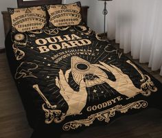 a bed covered in a black and gold cover with an image of a hand holding a fan