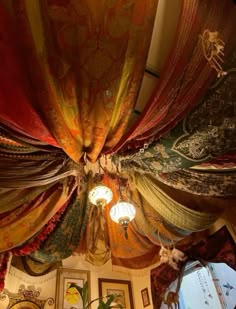 the ceiling is covered with colorful drapes and hanging chandelier, along with pictures on the wall