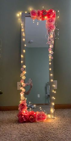 a mirror that has some lights on it and flowers in front of it, with the reflection