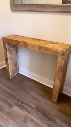 a wooden bench sitting on top of a hard wood floor next to a framed mirror