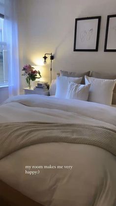 a bed with white sheets and pillows in a bedroom next to two framed pictures on the wall