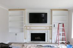 a living room with white built in bookshelves and a tv mounted on the wall