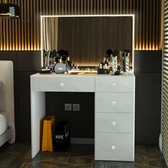 a white vanity with drawers and lights on it in front of a mirror that is lit up