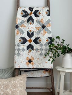 a quilt on a ladder next to a potted plant