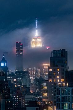 the city skyline is lit up at night, with skyscrapers visible in the background