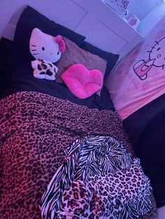 a hello kitty bed with pink and black sheets, pillows and blankets on top of it