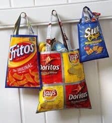 three grocery bags hanging from hooks on a white door with the word fritos printed on them