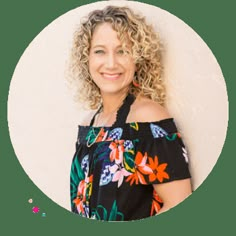 a woman with curly hair wearing an off the shoulder top and smiling at the camera