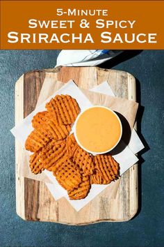 a wooden tray topped with cheetos next to a bowl of dipping sauce