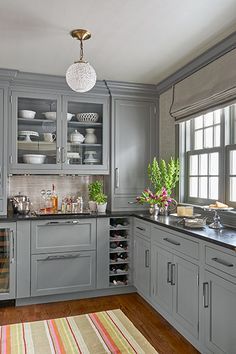 a kitchen with gray cabinets and striped rug