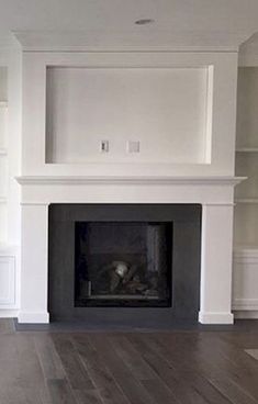 an empty living room with a fireplace and bookcases