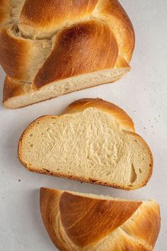 two loaves of bread sitting next to each other on a white counter top with one loaf cut in half