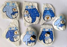 six painted rocks with snowmen on them and one is wearing a blue hat, scarf and mittens