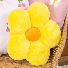 two pillows with yellow flowers on them sitting in a wicker basket next to each other