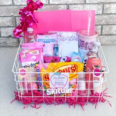 a pink basket filled with lots of different types of items next to a brick wall